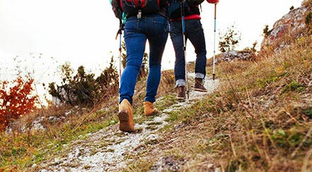Le gambe di una coppia di escursionisti mentre camminano in salita con i bastoni da trekking