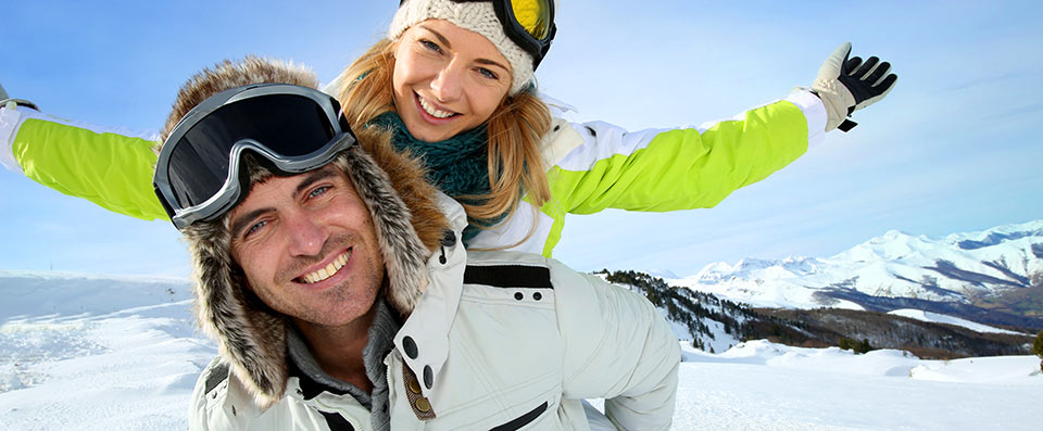 Paar mit Frau auf den Schultern von einem Mann, während Sie Spaß haben im Schnee